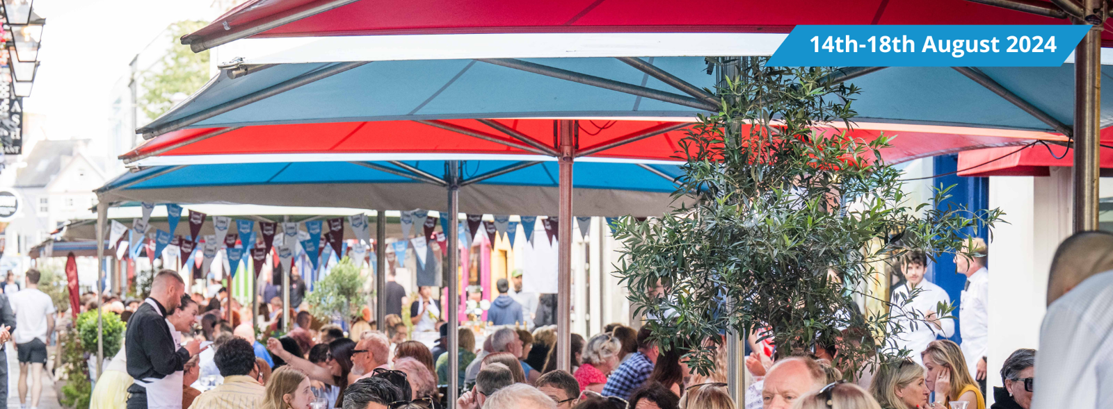 People dining on the street under blue and red umbrellas